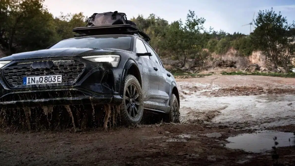 Vista lateral del Audi Q6 e-tron todoterreno en un terreno difícil, con sus neumáticos todoterreno y su diseño ampliado.