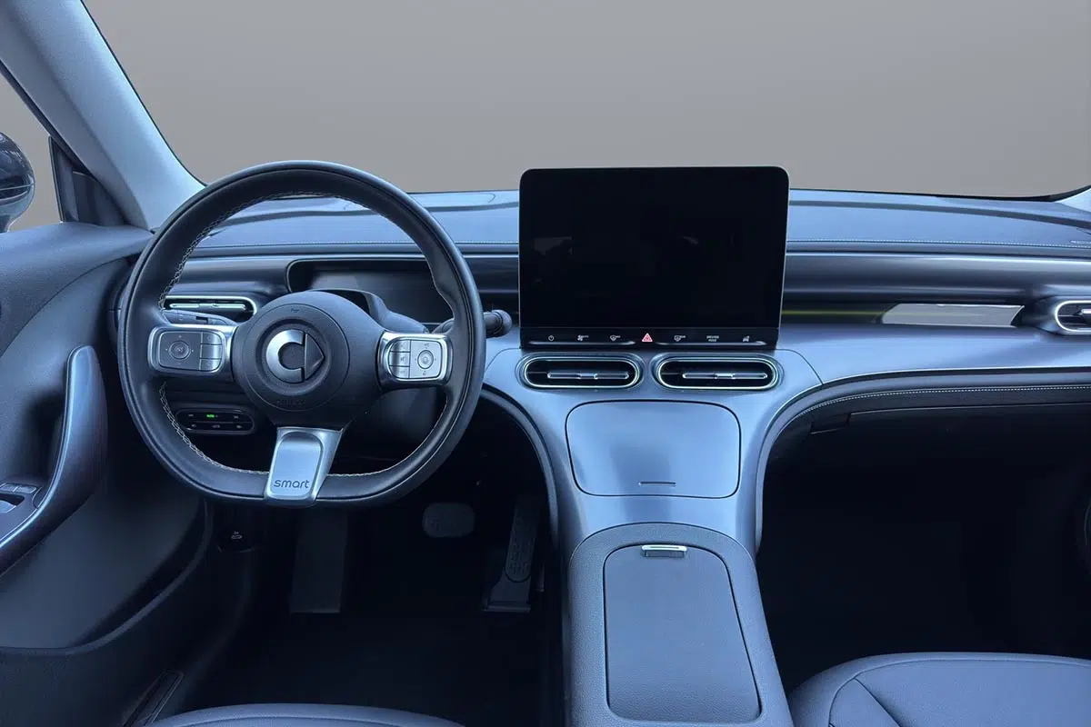 Vista interior del Smart #1 Pure, destacando un diseño moderno y minimalista. Una gran pantalla táctil central, un tablero digital y un volante ergonómico predominan en el habitáculo, ofreciendo una experiencia conectada e intuitiva.