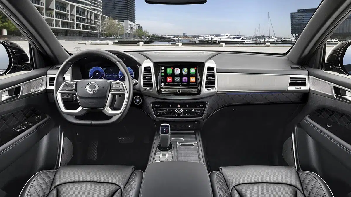 Vista del puesto de conducción del KGM Rexton 2025, destacando la pantalla táctil y la instrumentación digital.