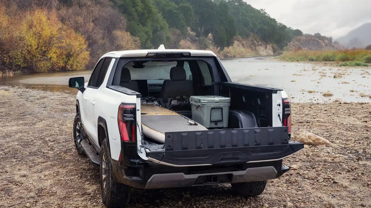 GMC Sierra EV AT4 2026 visto desde atrás con el portón MultiPro abierto y el compartimento eTrunk
