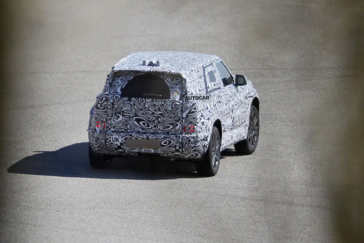 Vista trasera del Baby Defender camuflado en carretera con silueta cúbica