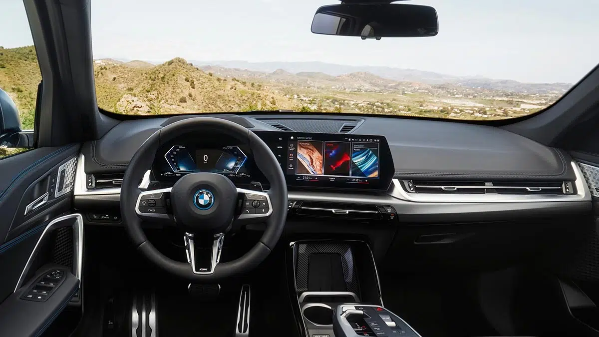 Cabina del BMW X1 xDrive30e 2025 con doble pantalla curva e interfaz iDrive 9