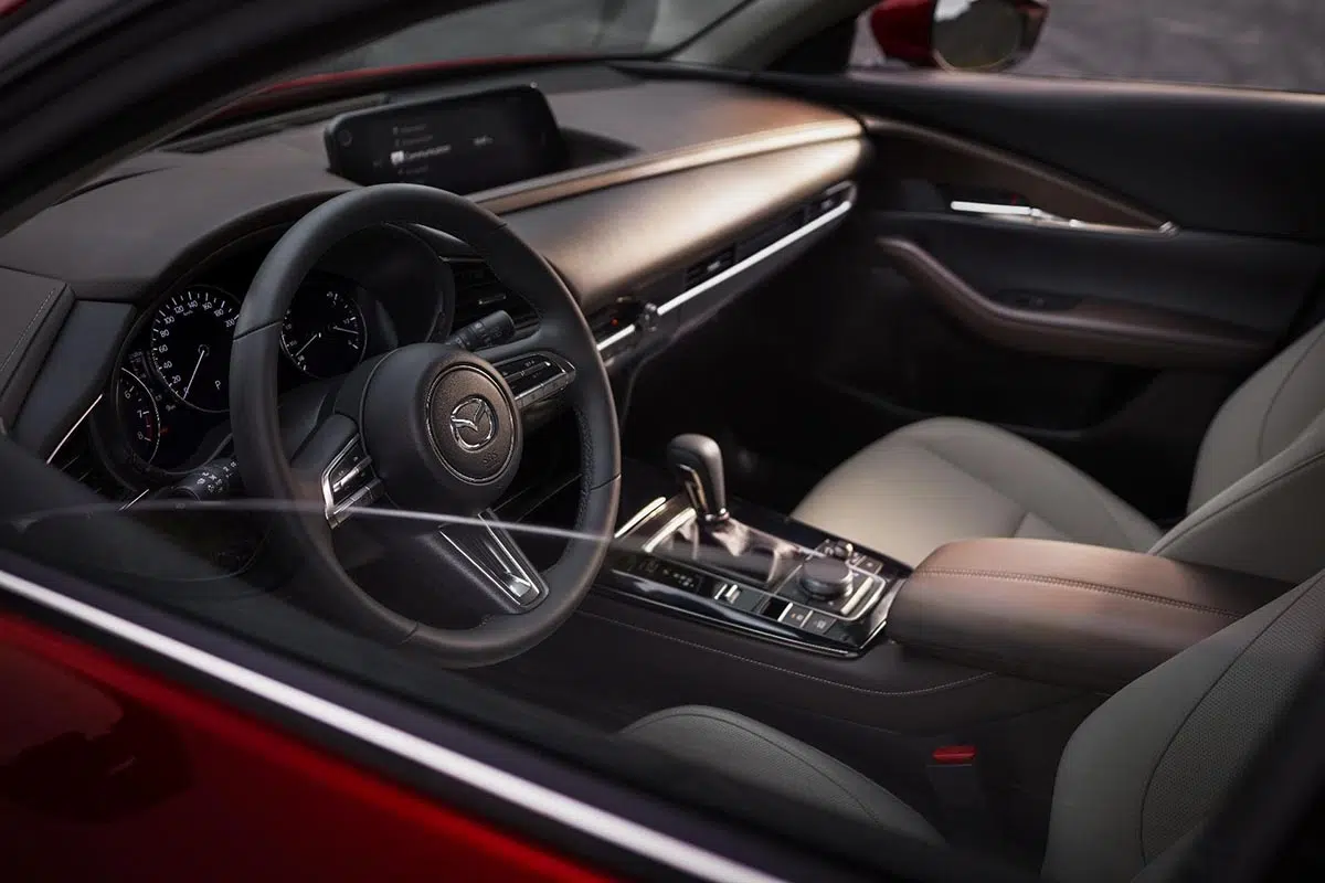 Vista lateral del puesto de conducción del Mazda CX-30 2025 con volante multifunción y pantalla central